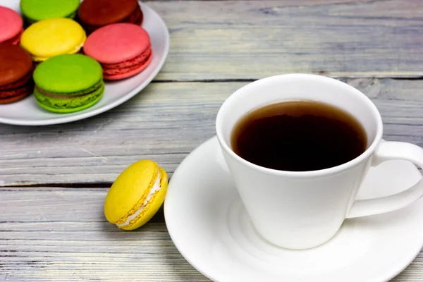 Bílý šálek kávy a malé barevné makrónové sušenky. — Stock fotografie