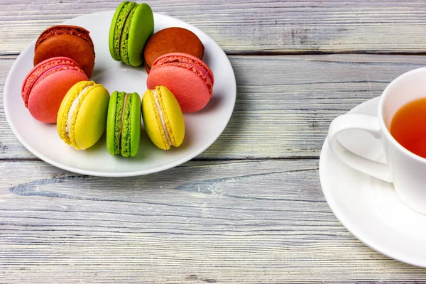 Beyaz tabakta makarna ve ahşap masada bir fincan çay. Fransız bisküvileri.