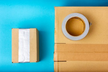 Birkaç karton kutu ve bir rulo koli bandı. Eşyalar paketleniyor.