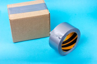 Yapışkan bant ve gri bantla mühürlenmiş karton kutu. Paketler yapıştırıcı bantla paketleniyor.