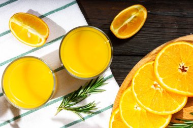 Portakal suyu üretme süreci. Portakal dilimleri ve bir bardak portakal suyu. Güneş ışığı. Yukarıdan görüntüle.