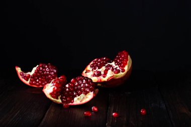 Kırık nar meyvesi. Karanlık bir masada nar tohumları..