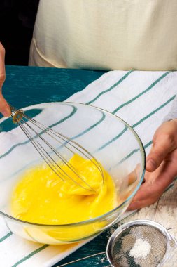 Kadın eli çırpılmış tavuk yumurtalarını çırpıyor. Turta hamuru yapma süreci. Mutfaktaki aşçılık süreci..