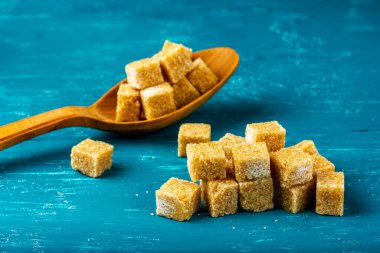Çubuk şeker taneleri. Tahta kaşıkta kahverengi şeker küpleri.