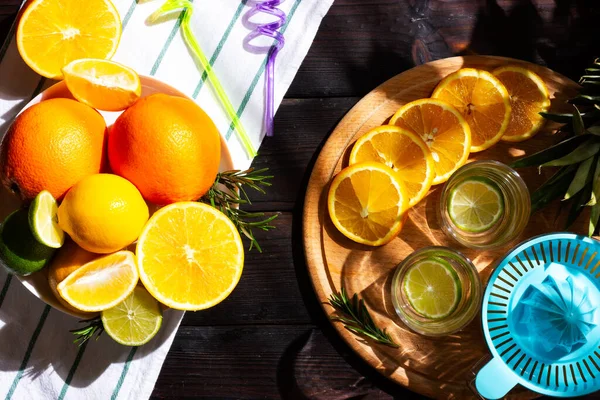 Portakallar ve limonlar plaj masasında. Tropikal meyvelerden kokteyl yapma süreci.