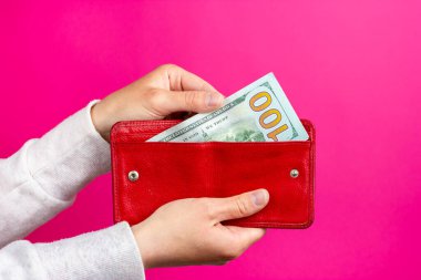 Kadınların elleri kırmızı bir cüzdandan bir dolar çıkarır. Para dolu cüzdan. Kırmızı cüzdan.