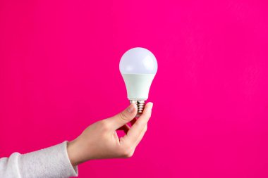 Bir kadının elinde LED ampul. Enerji tasarrufu lambası.