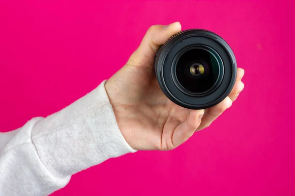 En kvinnlig hand håller i en fotolins. Objektiv för kameran. — Stockfoto