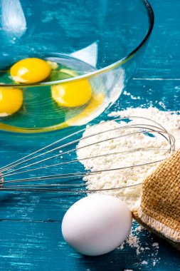 Tavuk yumurtası, un ve çırpı mutfak masasında. Hamur için gerekli malzemeler. Krep hamuru.