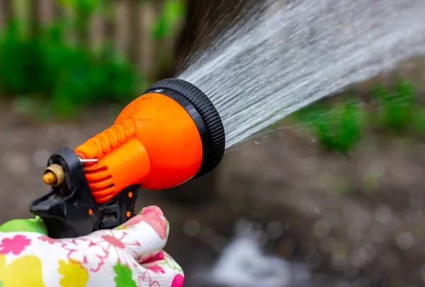 Spray d'acqua per il giardino. Annaffiare il giardino. Annaffiare il giardino sul retro. Irrigazione pistola in mano. — Foto Stock