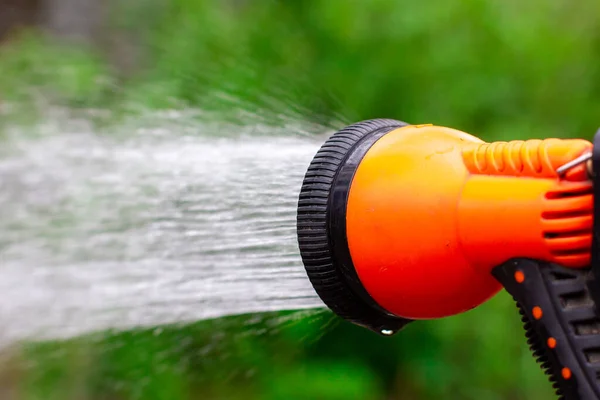 Spray all'arancia. Annaffiare il giardino verde. Pistola ad acqua per irrigazione. — Foto Stock