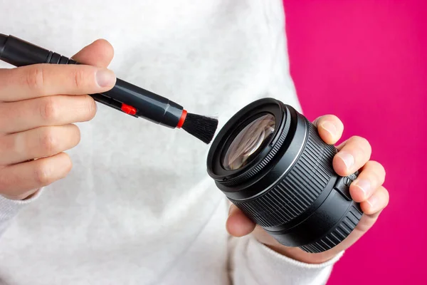 Limpiando la lente del polvo. El fotógrafo limpia la lente con un pincel. — Foto de Stock