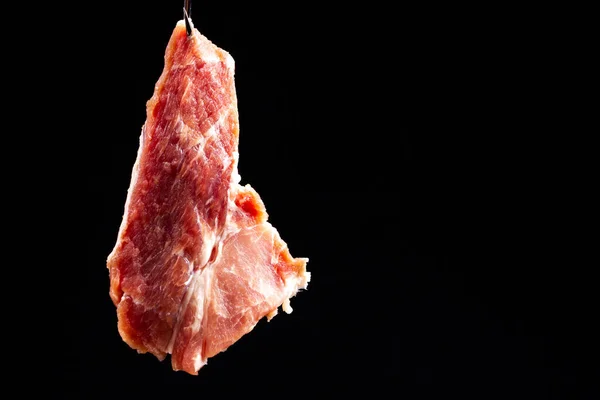 Bife de porco em um fundo preto. Carne crua. Carne de porco crua retroiluminada. — Fotografia de Stock