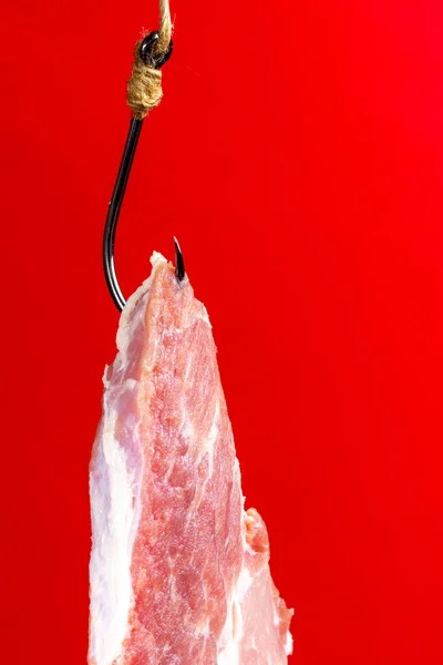 Egy nagy darab hús. Nyers steak közelről. Kampós csali. Sertéshús vörös háttérrel. Ragadozócsapda. — Stock Fotó