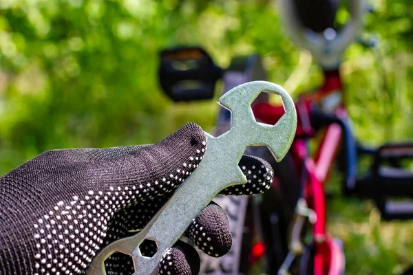 El ele tutuşun. Bisiklet tamiri. Eldivenli eller bisiklet anahtarını tutar. Bisiklet servisi. — Stok fotoğraf