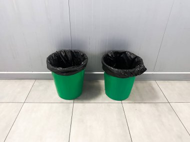 Fayanslı bir odada siyah çizgili iki yeşil çöp kutusu. Çok çeşitli kullanım alanları için uygun