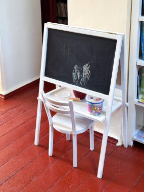 Samimi bir odada, tahta zeminde çocuk tahtası ve sandalye. Yaratıcı ya da profesyonel projeler için harika