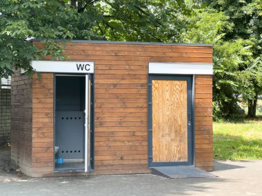 Ağaçların altındaki parktaki modern ahşap umumi tuvalet. Çok çeşitli kullanım alanları için uygun