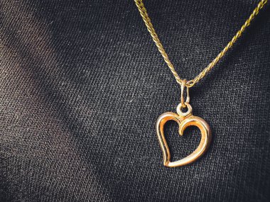 Koyu dokulu kumaşta altın kalp kolyesi. Yaratıcı ve ticari kullanım için ideal