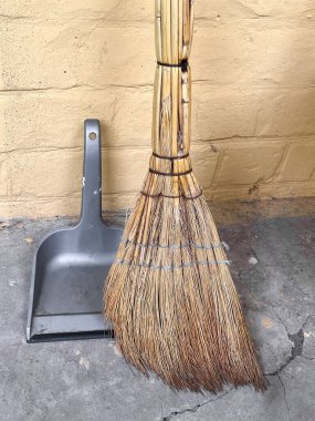 Sarı tuğlalı duvara dayanmış bir süpürge ve faraş. Yaratıcı ve ticari kullanım için ideal