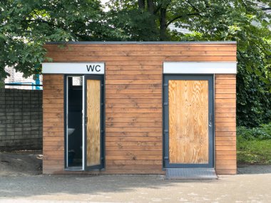 Ağaçlarla çevrili ahşap umumi tuvalet binası. Yaratıcı ve ticari kullanım için ideal