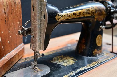 A vintage Singer sewing machine with intricate details sits on a dark wooden table, evoking a sense of craftsmanship and history.