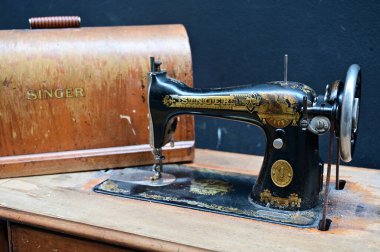 A vintage Singer sewing machine with intricate details sits on a dark wooden table, evoking a sense of craftsmanship and history.