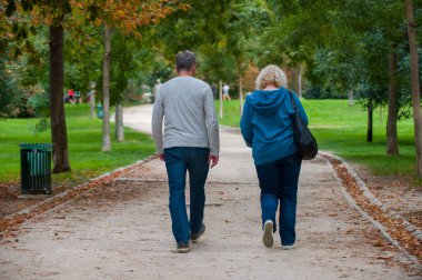Sonbaharda dışarıda yürüyüş yapan iki insanın arka görüntüsü.
