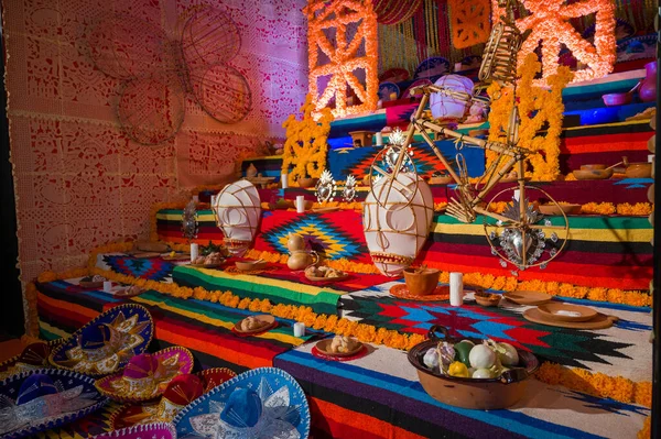 Ölü sunağın canlı günü kadife çiçekleri mumları ve papel picado ile süslenmiş.