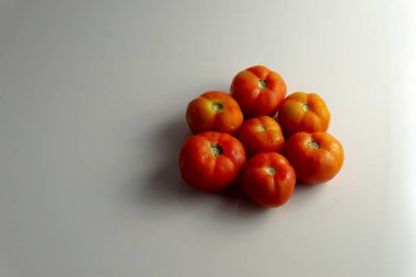 Kırmızı sulu domatesler beyaz arka planda üst üste dizilmişler.