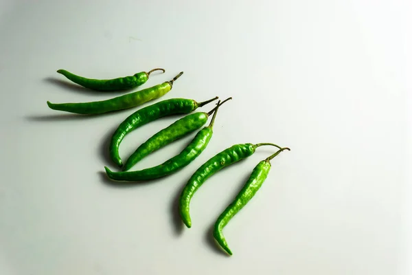 Group of green chilly stacked together on a white background