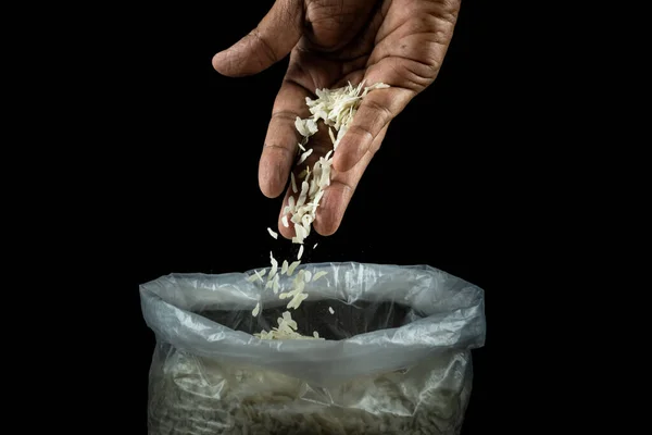 Human hand pouring thin flattened rice into a bowl placed on a dark table