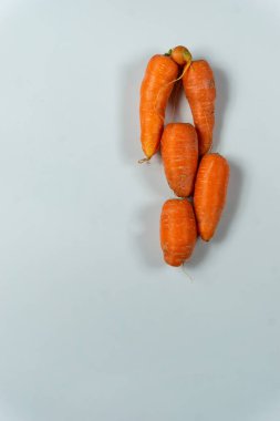 Taze pişmemiş ham kırmızı havuçlar, fotokopi alanı olan beyaz bir arka planda üst üste dizilmiş.
