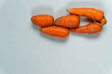 Taze pişmemiş ham kırmızı havuçlar, fotokopi alanı olan beyaz bir arka planda üst üste dizilmiş.