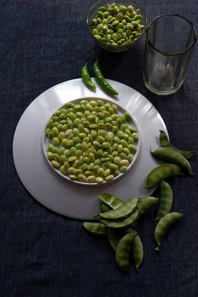 Fresh green lima beans stacked together on a white plate with selective focus