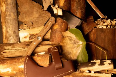 Hayat hala karanlık arka planda, kütükler, bıçaklar ve baltalarla dolu.