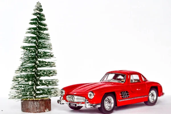 red toy car next to christmas or new year tree, holiday card concept