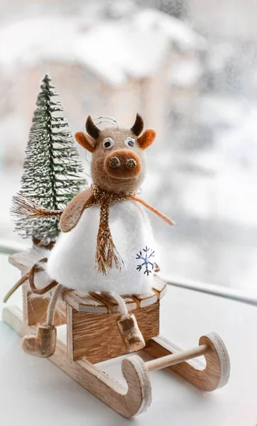 cow bull symbol of the new year 2021, sits on a sleigh made of wood in a white dress, a star is drawn, the background is blurred