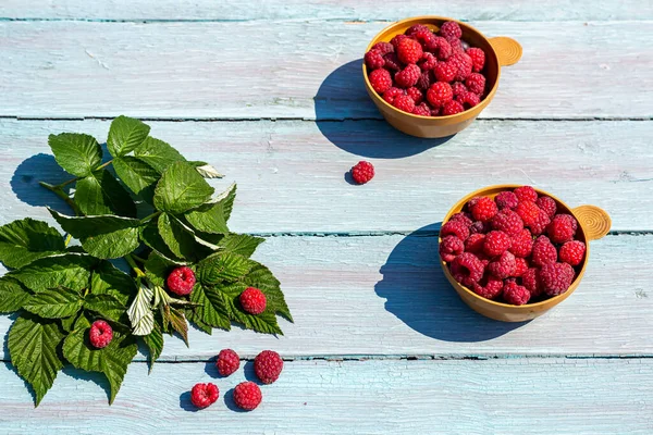 Parlak yaz konsepti, doğada kırsal tarzda kahvaltı. Mavi ahşap arka planda, bir fincanda olgun ahududular. Yatay fotoğraf.
