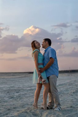 Dikey fotoğrafçılık. Mutlu ilişkiler ve aile seyahati kavramı. Genç adam ve kadın sahilde romantik bir çift gibi sarılıp öpüşüyorlar..