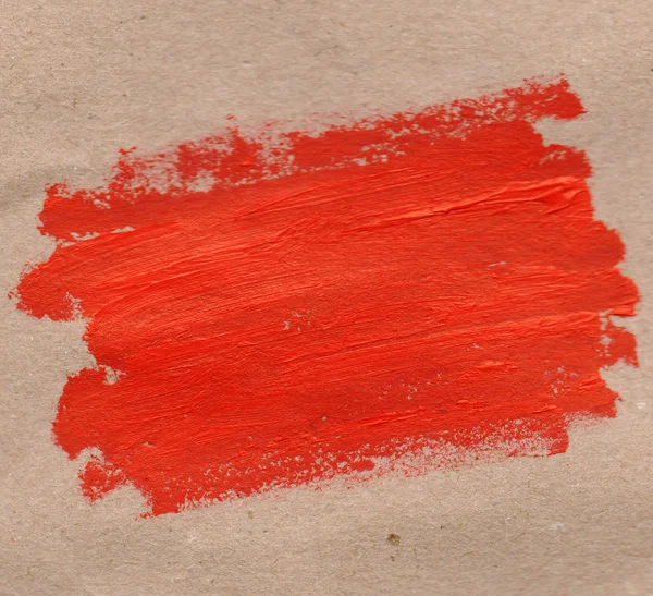 棕色纸背景上红色油漆的纹理斑点。真正的材料。手画。矩形形状 — 图库照片