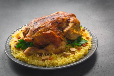 Kabsa - uzun tahıllı basmati pilavından yapılmış Arap yemeği, tam tavuk, soğan, baharatlar: kakule, safran, tarçın, defne yaprakları. Badem ve kuru üzümle süslenmiş. Suudi Arabistan yemeği. Gri arkaplan
