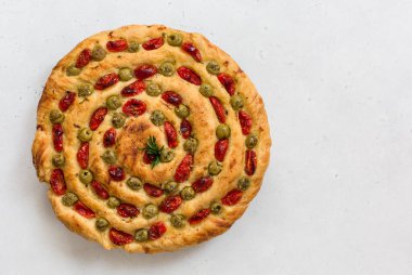 Ev yapımı İtalyan düz ekmeği Focaccia contorta. Zeytin, zeytin yağı, biberiye, domates. Geleneksel tarif. Vejetaryen. Beyaz beton doku arkaplanı.