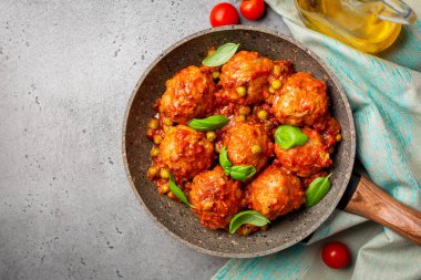Yeşil bezelye ve fesleğen yapraklı domates soslu hindi köftesi. Düz, gri beton arka plan. Boşluğu kopyala.