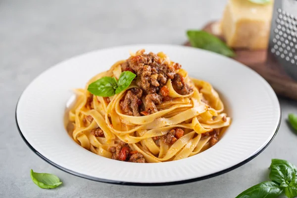 Tagliatelle al ragu. Bolonez soslu İtalyan makarnası. Yüce melek. Arka planda ekstra sert peynir.