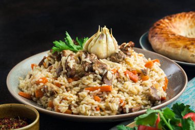 Uzbekistan national dish - plov, made from: uzbek Devzira rice, lamb, onion, carrot, spiced with cumin, coriander, barberries, red pepper, prepared with head of garlic.Traditional bread on background. clipart