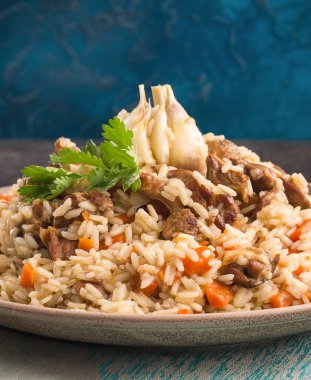 Özbekistan ulusal yemeği - plov: Özbek Devzira pirinci, kuzu eti, soğan, havuç, kimyon, kişniş, böğürtlen, kırmızı biber ve sarımsak ile hazırlanmış. Mavi arkaplan, kapat.