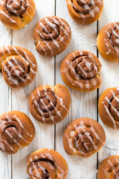 Tahta beyaz arka planda ev yapımı tarçınlı çörekler..