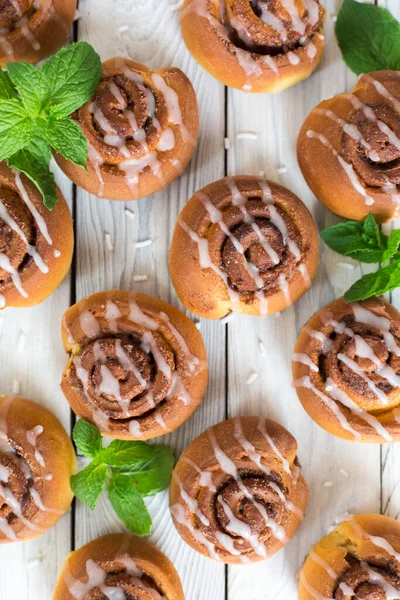 Tahta beyaz arka planda ev yapımı tarçınlı çörekler. Dikey resim.