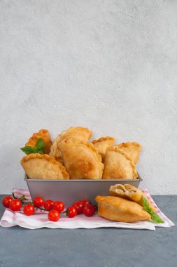 Ev yapımı Panzerotti. Güney İtalya usulü kızarmış cips. İçinde mozzarella, mortadella dolgu ve domates var. Işık arkaplanı, kopyalama alanı.